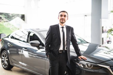 Profesyonel satıcı yeni bir arabanın önüne gülümseyen