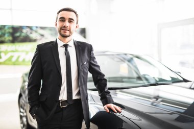 Profesyonel satıcı yeni bir arabanın önüne gülümseyen