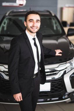 Bayilik yeni araba önünde ayakta yakışıklı genç klasik araba satıcısı