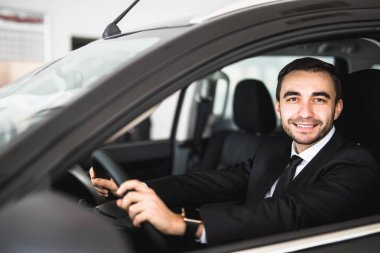 bir arabanın penceresinden bakarak gülen adam