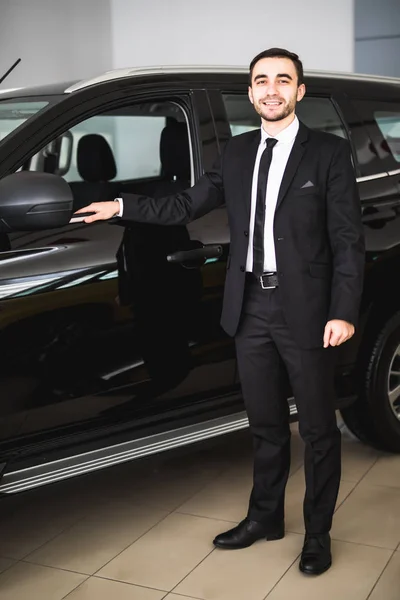 Bonito jovem empresário de terno de pé perto do carro — Fotografia de Stock