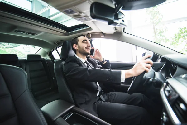 Hombre usando su teléfono mientras conduce el coche. Hombre de negocios conductor hablar teléfono blanco coche — Foto de Stock