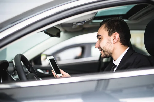 Бизнесмен в автомобиле читает сообщение или смт на смартфоне — стоковое фото