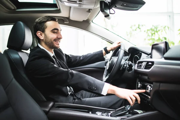 Primer plano de hombre joven en traje coche de conducción y cambiar algún botón en el panel del coche — Foto de Stock