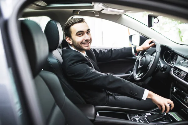 Transporte, viagem de negócios, destino e conceito de pessoas - close-up de homem jovem de terno condução carro olhar para a câmera — Fotografia de Stock