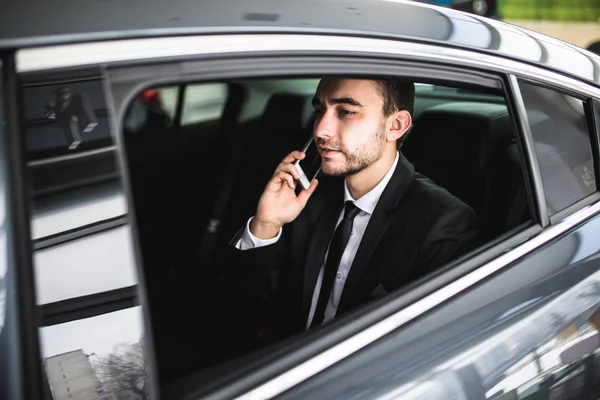 Seriöser Geschäftsmann benutzt sein Handy im Auto — Stockfoto