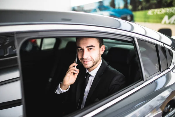 Homem de negócios sério usando seu telefone em seu carro — Fotografia de Stock