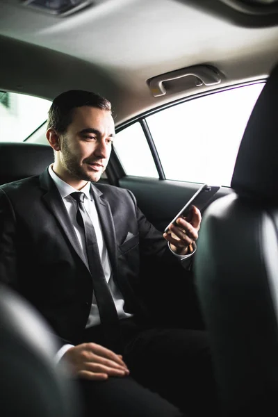 Pewni, młody biznesmen, ustawienie jego inteligentny telefon i patrząc na kamery, siedząc w samochodzie — Zdjęcie stockowe