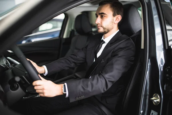 Joven sonriendo mientras conduce en su coche — Foto de Stock