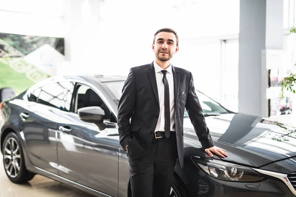 Profesyonel satıcı yeni bir arabanın önüne gülümseyen