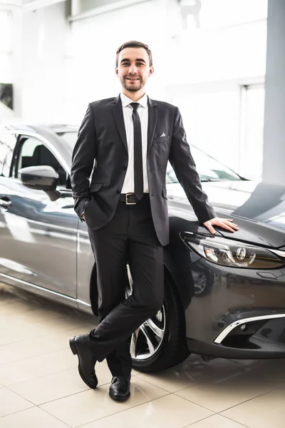 Vendedor profissional sorrindo na frente de um carro novo — Fotografia de Stock