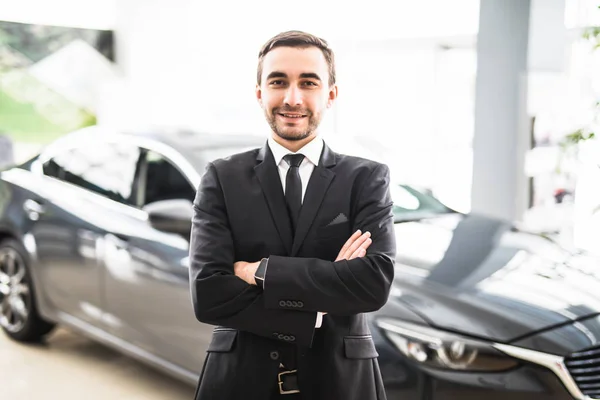Relajado joven hombre de negocios o vendedor con las manos cruzadas delante del coche — Foto de Stock