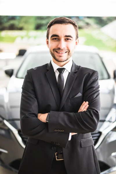 Entspannter junger Geschäftsmann oder Verkäufer mit vor dem Auto verschränkten Händen — Stockfoto