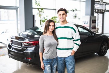 Gülümseyen çift ayakta önünde bir araba, yeni araba showroom