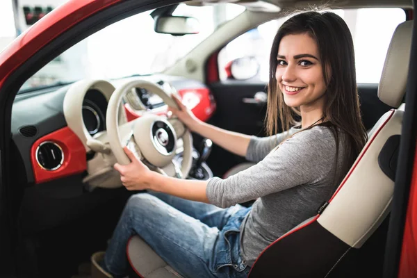 Jovem mulher atraente sorrindo e olhando para a câmera enquanto dirige um carro — Fotografia de Stock