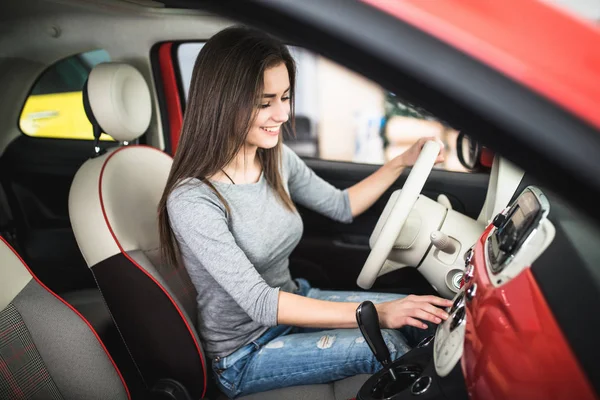 Vrouw rijden nieuwe en moderne auto en draai knop op dashboard paneel in auto — Stockfoto