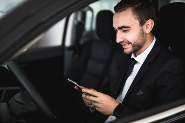Handsome businessman using smartphone in car on passanger seat — Stock Photo, Image