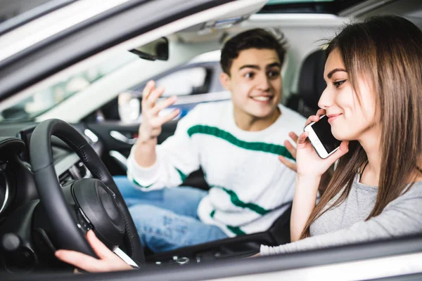 Боковой портрет пары в машине. Мужчина с криком и жестом, пока девушка разговаривает по телефону в машине — стоковое фото