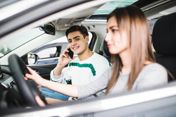 Side portrait of couple in car. Man speak phone on passanger seat while woman drive a car — Stock Photo, Image