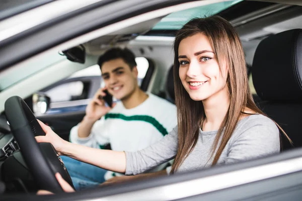 Retrato lateral de casal no carro. Homem fala telefone no assento do passageiro enquanto a mulher dirige um carro — Fotografia de Stock