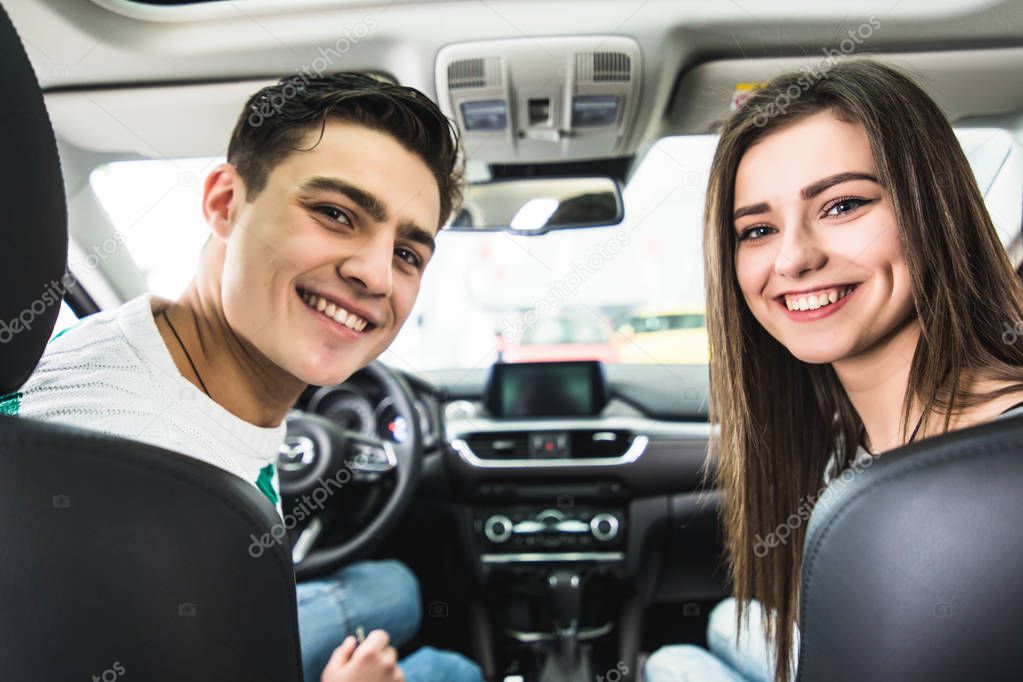 Attractive couple chooses a new car in the showroom, sitting in the car
