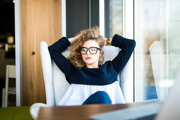 Affärskvinna som avkopplande arbeta på kontor skrivbord lade tillbaka vilar på stol med händerna bakom huvudet. — Stockfoto