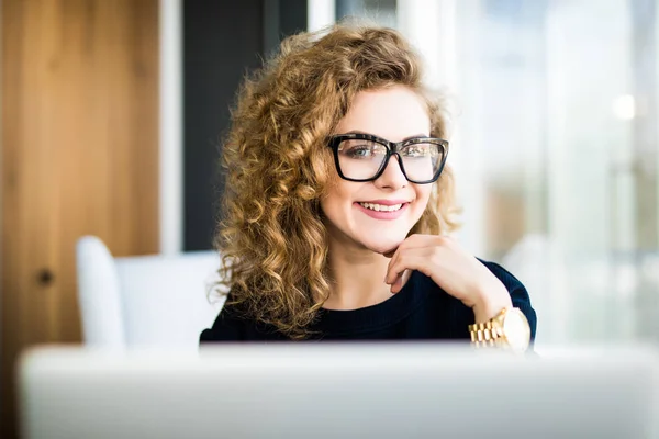 Retrato de una joven mujer de negocios en gafas usando portátil en la oficina — Foto de Stock