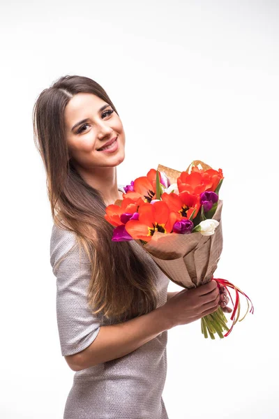 Beautiful girl in the grey dress with flowers tulips in hands on a light background — Stock Photo, Image