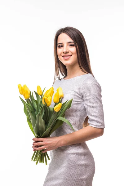 Bella ragazza in abito con fiori gialli tulipani in mano su uno sfondo bianco — Foto Stock