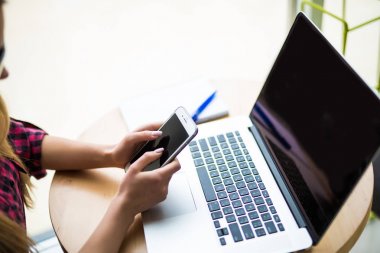 Modern ofis iç adlı bilgisayarda çalışırken akıllı telefon kullanarak eller Close-Up