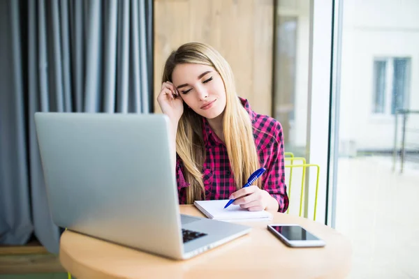 Una mujer trabajando en una computadora en un café. Cara cansada de mujer . — Foto de Stock