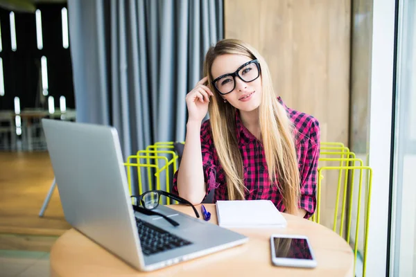 Una mujer trabajando en una computadora en un café. Cara cansada de mujer . — Foto de Stock