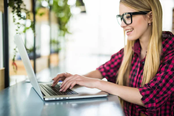 若い女性起業家作業の座っている机のオフィスで彼女のラップトップ コンピューター上で入力側からの眺め — ストック写真