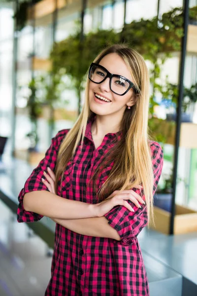 Smiling woman, crossed arms in modern office