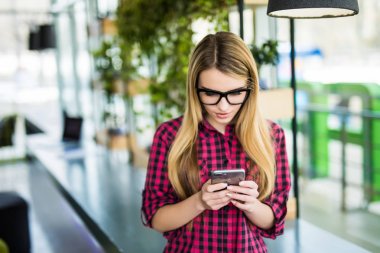 Modern ofis binaları içinde belgili tanımlık geçmiş ile bir akıllı telefon kullanan girişimci kadın