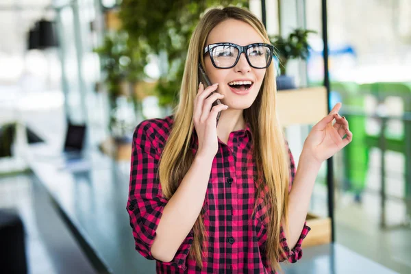 Freelancer mujer feliz hablando en el teléfono móvil con edificios de oficinas en el fondo — Foto de Stock