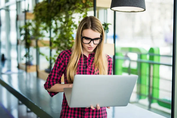 Hermosa señora independiente de negocios en ropa casual inteligente está utilizando un ordenador portátil, mirando a la computadora portátil en la oficina moderna — Foto de Stock