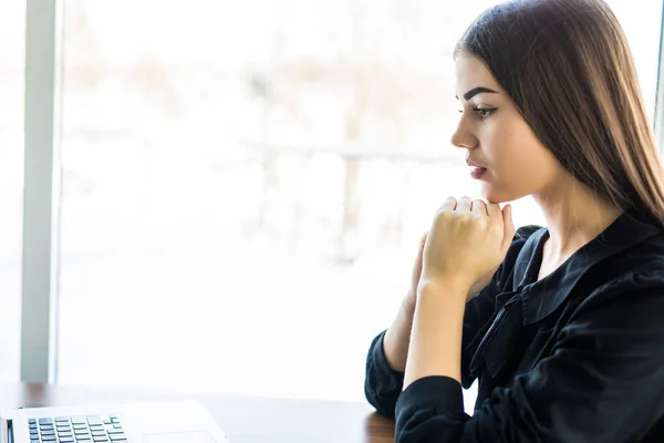 Chica joven usando su computadora portátil en la cafetería y mirar la pantalla — Foto de Stock