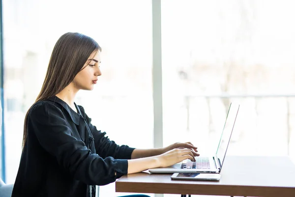 Vista lateral de la hermosa mujer joven utilizando el ordenador portátil en la cafetería — Foto de Stock