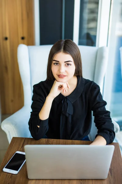 Bovenaanzicht, jonge zakenvrouw zit aan Bureau en on line werkt op laptop tijdens het gebruik van de smartphone. Student leren online. — Stockfoto