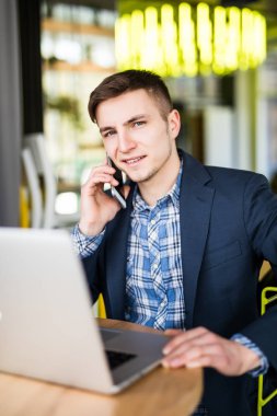 Laptop ile çalışma ve kamera göz istemci ile telefonda konuşurken genç serbest meslek