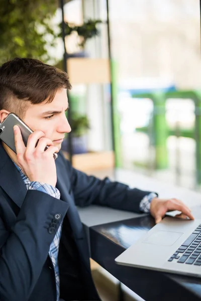 Mladí na volné noze práce s notebookem a mluví o telefonu s klientem — Stock fotografie