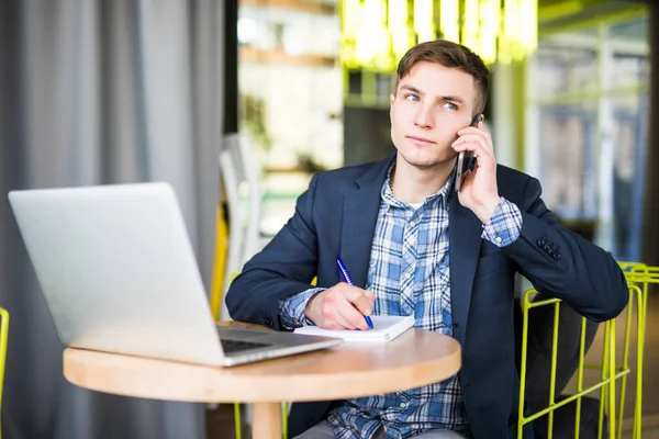 Hombre en el teléfono y escribir en el cuaderno en su oficina — Foto de Stock