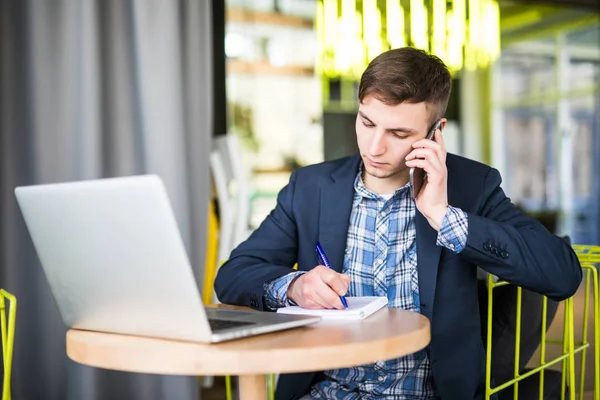 Hombre en el teléfono y escribir en el cuaderno en su oficina — Foto de Stock