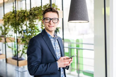 Genç adam cep telefonuyla ofis windows