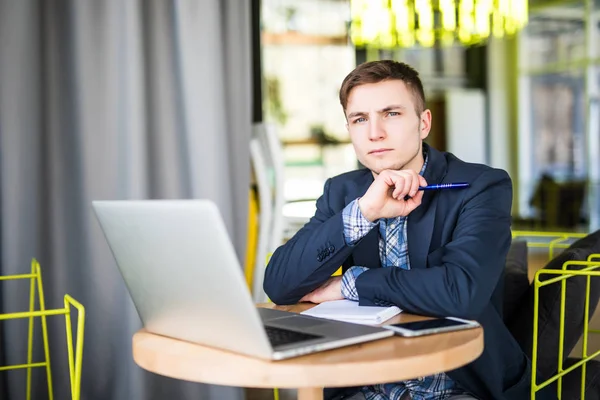 Tensed joven que trabaja en el ordenador portátil en la mesa de café y pensando — Foto de Stock