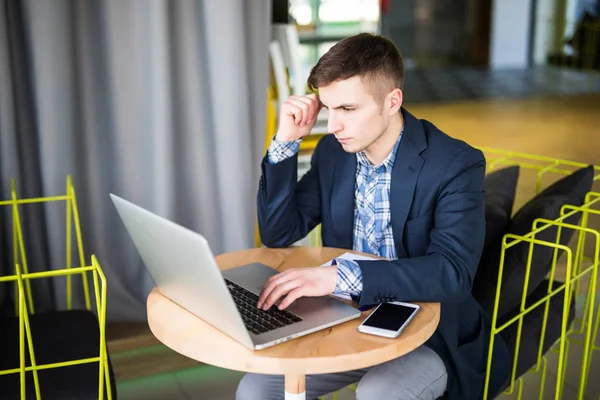 Tensed joven que trabaja en el ordenador portátil en la mesa de café y pensando — Foto de Stock