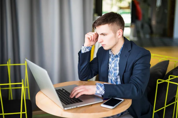 Jeune homme tendu travaillant sur ordinateur portable à la table de café et de penser — Photo
