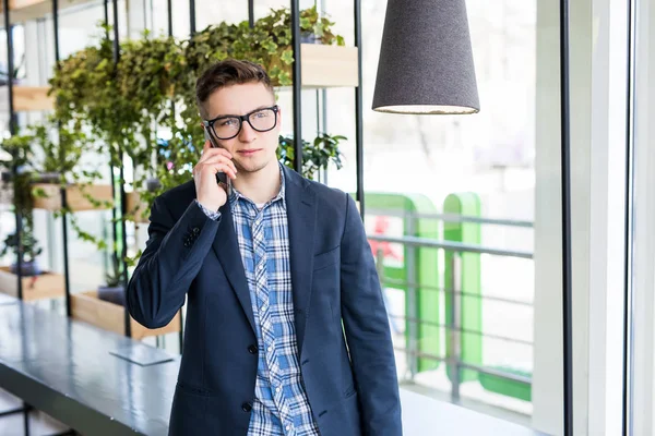 캐주얼 셔츠와 안경 직장에서 휴대 전화에 있는 매력적인 백인 남자의 초상화. — 스톡 사진