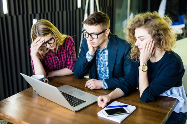 Three upset friends online using a laptop with problems and sad emotions in a coffee shop — Stock Photo, Image